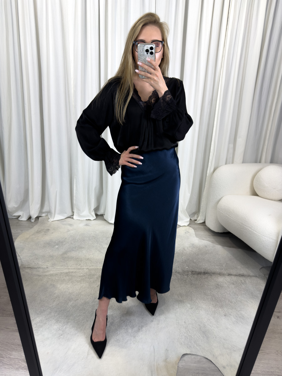 Spódnica Satine Navy z połyskującej satyny w odcieniu granatowym, o długości maxi, zestawiona z czarną bluzką z koronką – elegancka stylizacja idealna na wieczór i formalne okazje.