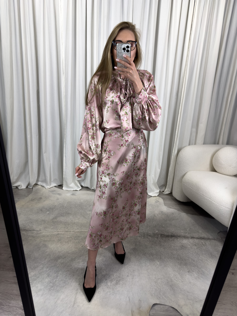 Komplet satynowy Vintage z różową koszulą z kokardą i spódnicą midi z kwiatowym nadrukiem – romantyczna stylizacja w stylu retro, idealna na wyjątkowe okazje. Fotografia modelki na białym tle.