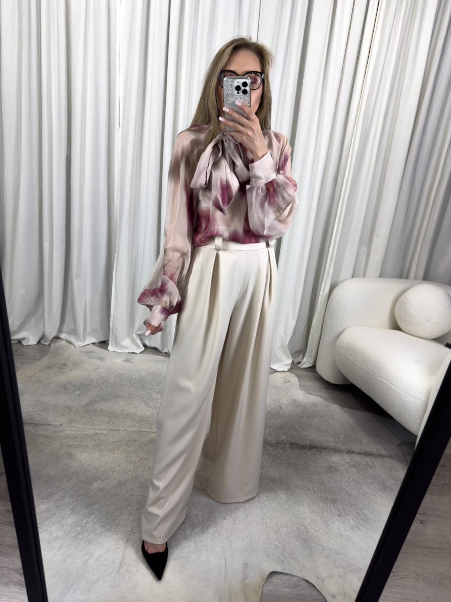 Stylowa koszula Alice burgundowa z artystycznym nadrukiem i dekoracyjną kokardą przy dekolcie, zestawiona z szerokimi, kremowymi spodniami palazzo – elegancka stylizacja dla kobiet ceniących klasykę z nowoczesnym akcentem.