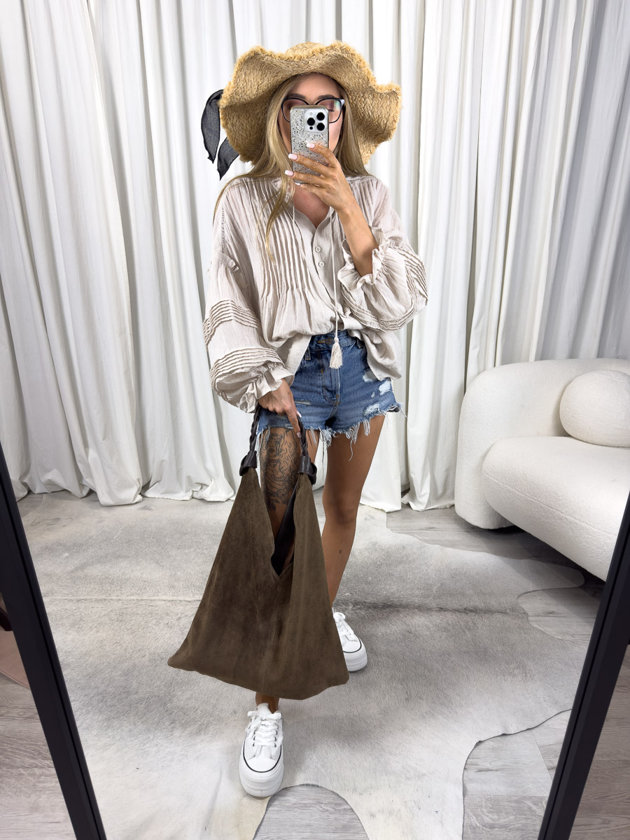 Zdjęcie produktowe sklepu internetowego z odzieżą damską – modelka ubrana w koszule Boho w kolorze beżowym marki Wiya, jeansowe szorty oraz dodatki typu słomiany kapelusz, zamszowa torebka shoperka
