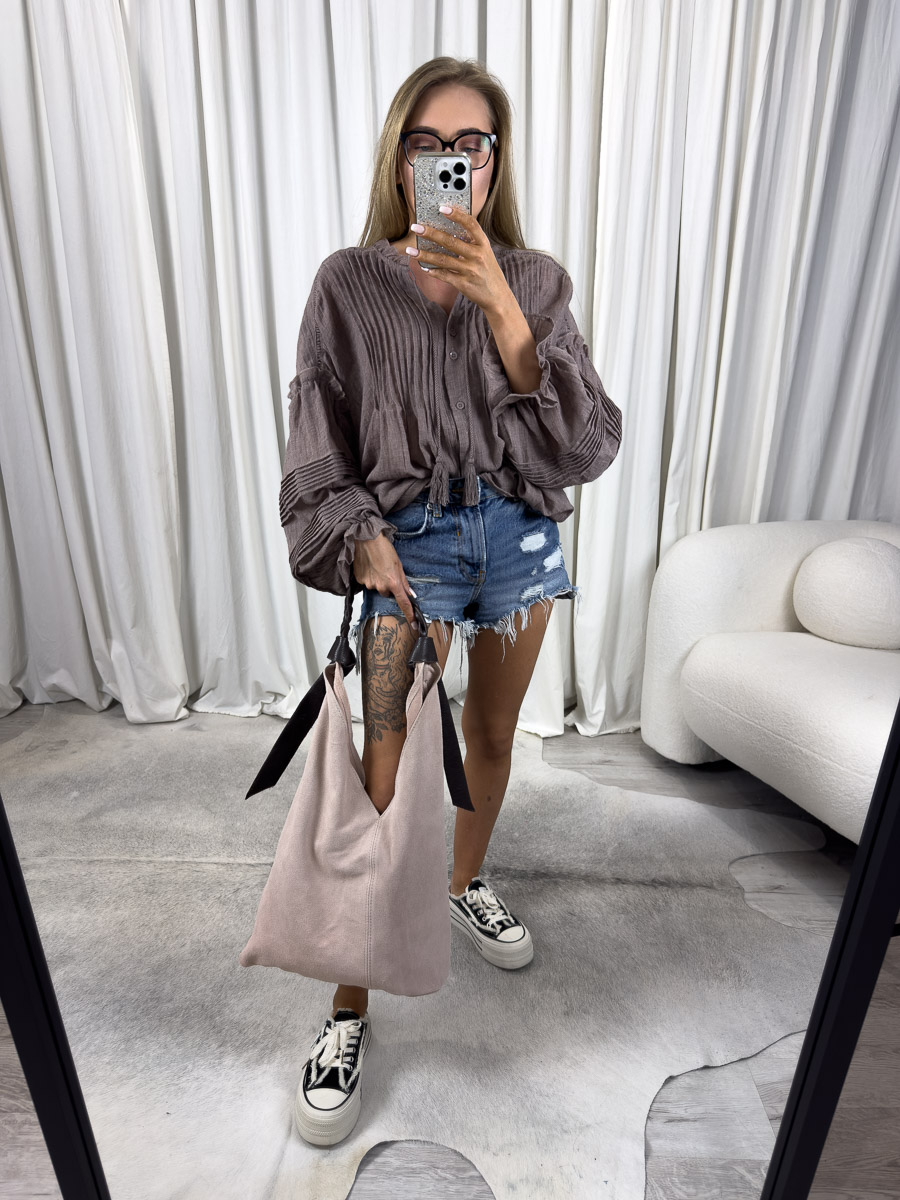 Zdjęcie produktowe sklepu internetowego z odzieżą damską – modelka ubrana w koszule Boho w kolorze brązowym marki Wiya, jeansowe szorty oraz trzymająca w ręce zamszową torebkę