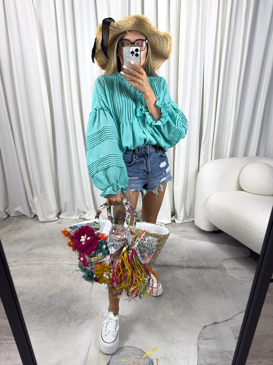 Zdjęcie produktowe sklepu internetowego z odzieżą damską – modelka ubrana w koszule Boho w kolorze turkusowym marki Wiya, jeansowe szorty oraz dodatki typu słomiany kapelusz, wiklinowa torebka koszyk