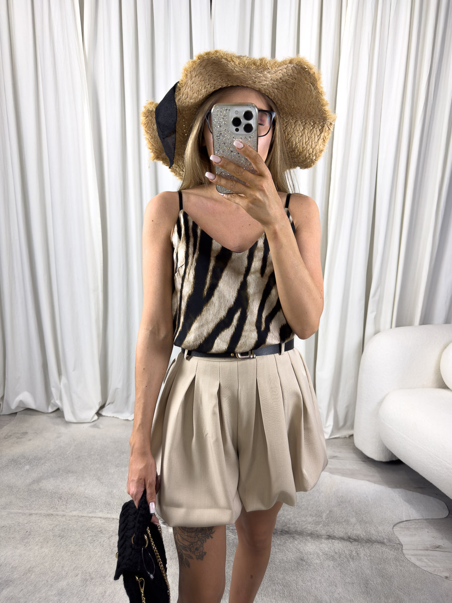 Zdjęcie produktowe sklepu internetowego z odzieżą damską – modelka ubrana w top satynowy Animal Print 3, beżowe szorty i słomiany kapelusz