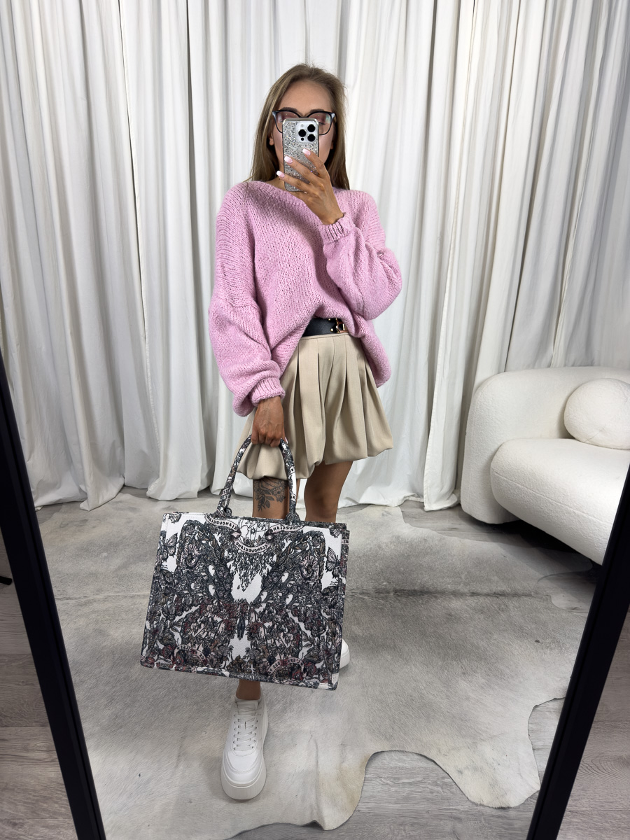 Kobieta w swetrze oversize Balloon różowym, plisowanej spódnicy i sneakersach, z kolorową torebką – stylizacja casualowa na lato.