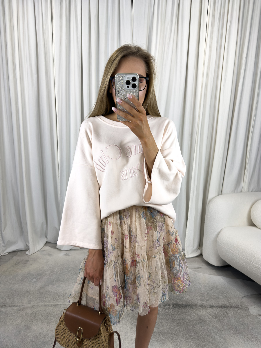 Lekka bluza oversize Club kremowa – bluza w kolorze kremowym z haftem, stylizacja z plisowaną spódnicą w kwiaty i wiklinową torebką.