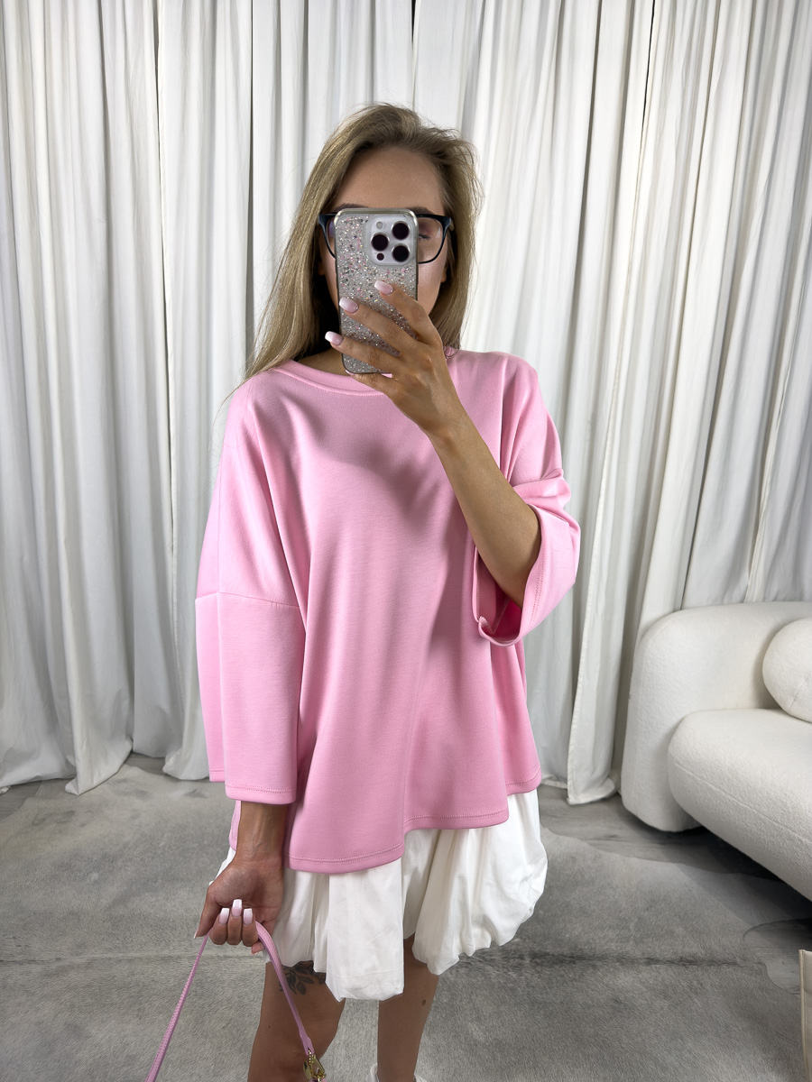 Modelka w różowym t-shircie oversize Silky, zestawionym z białą spódnicą i pastelową torebką – stylizacja casualowa w stylu soft girl.