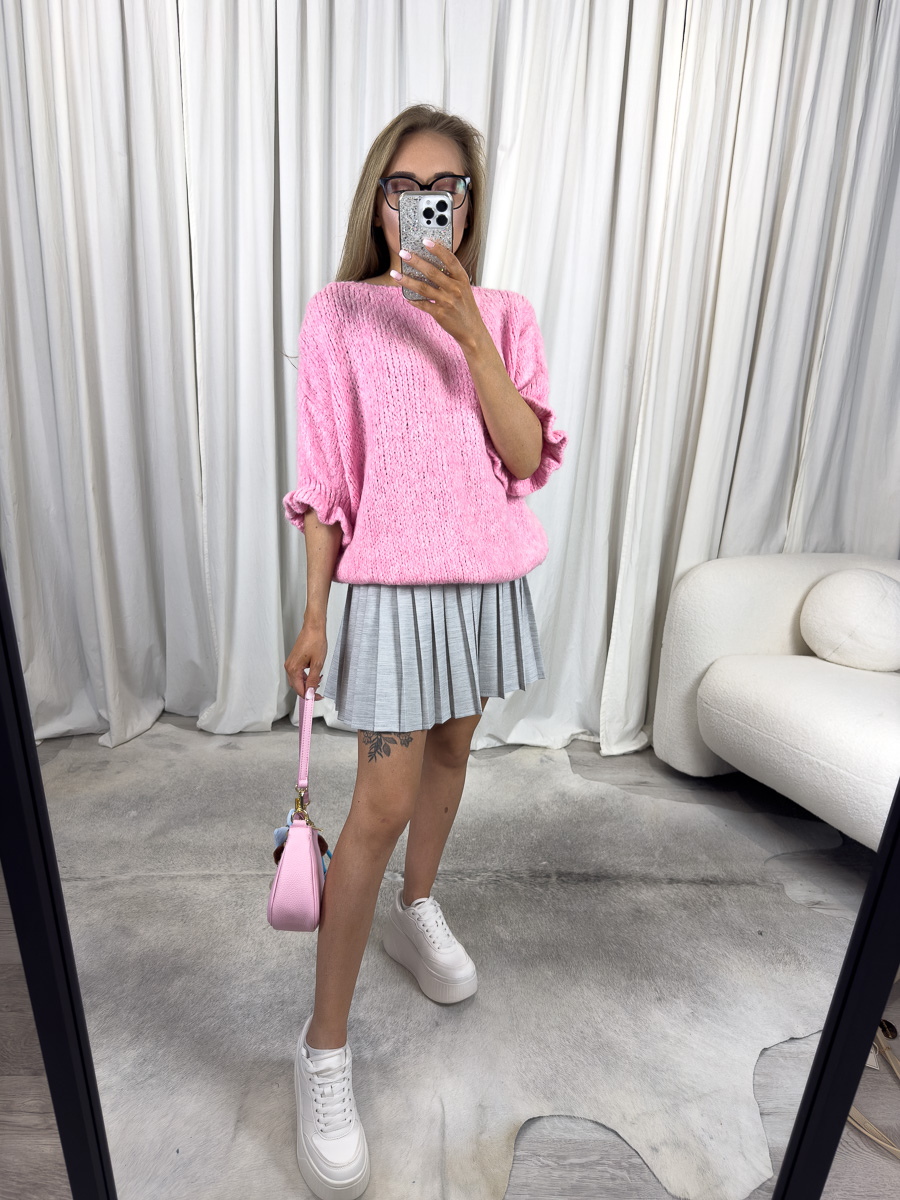 Sweter pastelowy Flounce różowy – kobieta w swetrze z bufkami i plisowaną spódnicą