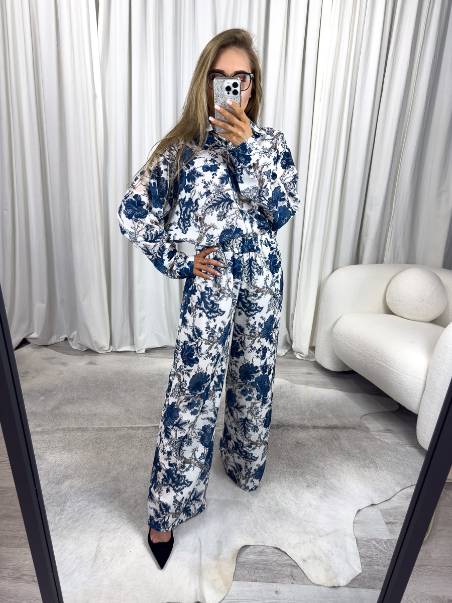 Modelka w letnim komplecie w kwiaty Vogue – koszula i spodnie z szerokimi nogawkami w biało-niebieski kwiatowy wzór, stylizacja na lato, modne komplety damskie.