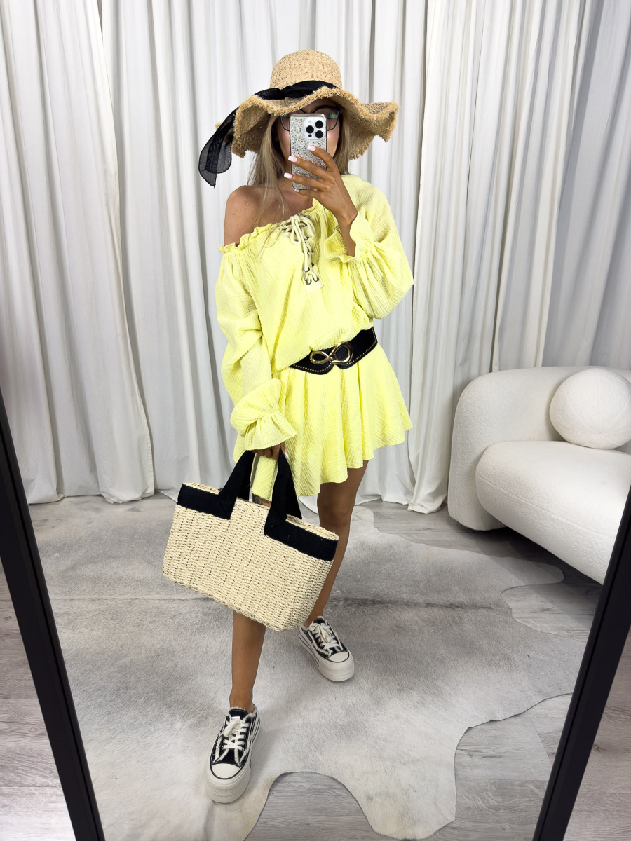 Modelka w kombinezonie muślinowym Safari z odkrytym ramieniem, wiązaniem na dekolcie i szerokim paskiem w talii. Zdjęcie produktowe sklepu internetowego z odzieżą damską.