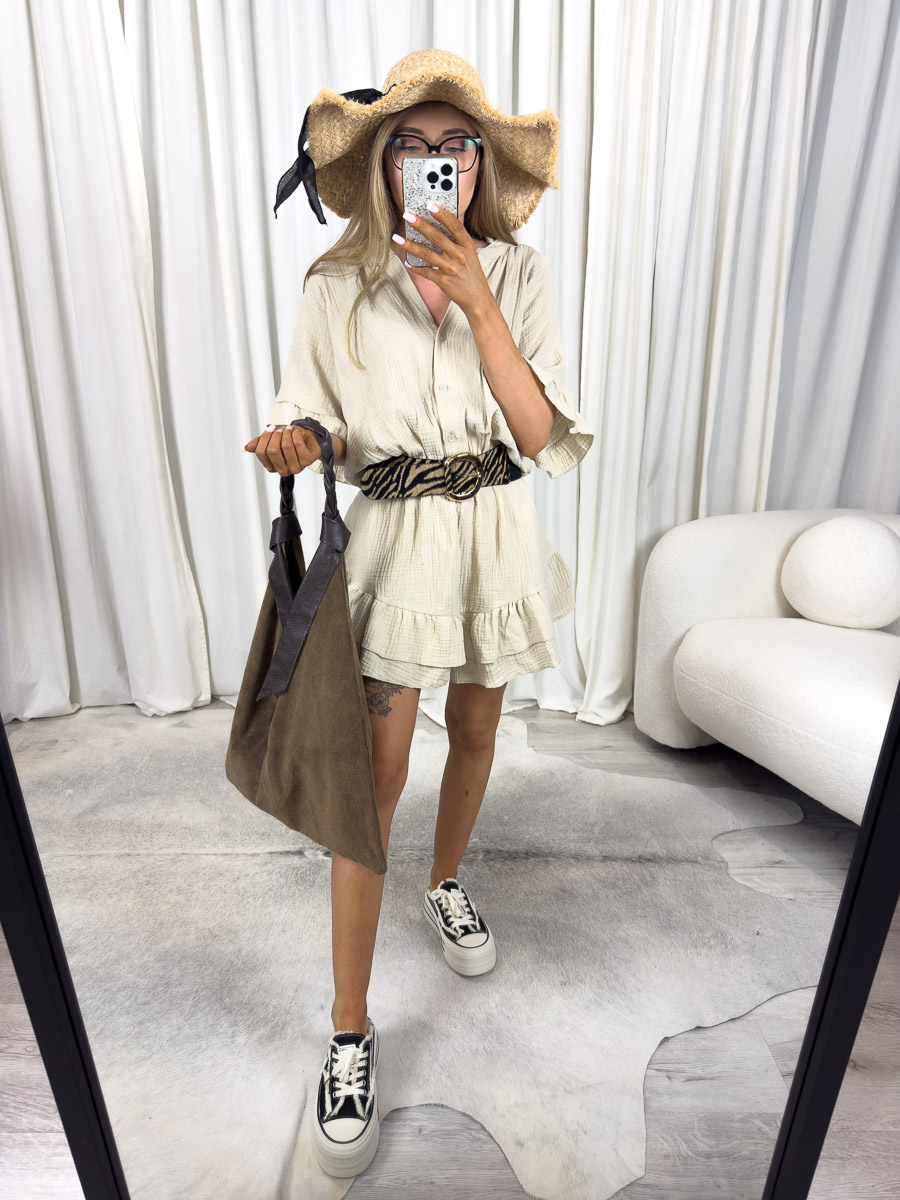 Modelka w kombinezonie muślinowym Soho z falbanami, elastycznym pasem i rozpinanym dekoltem, w stylizacji z kapeluszem i torbą. Zdjęcie produktowego sklepu internetowego z odzieżą damską.