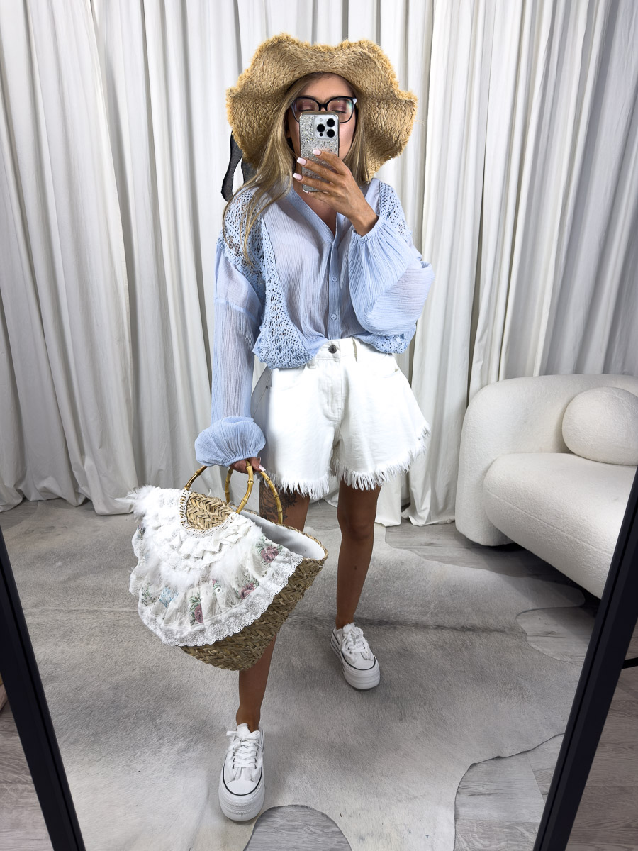 Zdjęcie produktowe sklepu internetowego z odzieżą damską – modelka w koszuli Malta Wiya błękitna, białych szortach z frędzlami, wiklinowej torbie i kapeluszu