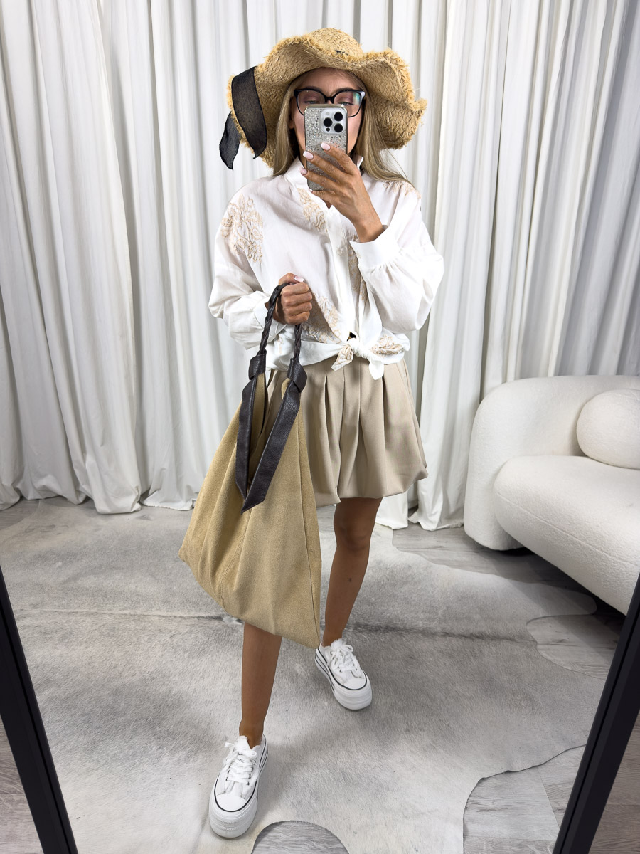 Zdjęcie produktowe sklepu internetowego z odzieżą damską – modelka w koszuli Ricamato beżowej z haftem etno, zawiązanej w pasie, jeansowych szortach i wiklinowej torbie