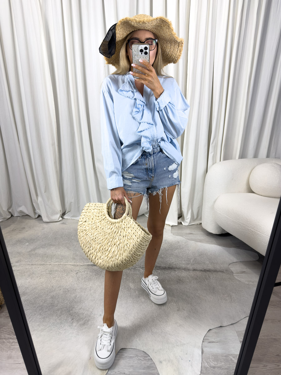 Zdjęcie produktowe sklepu internetowego z odzieżą damską – modelka w koszuli boho Vita Gioya z falbaną, szortami i wiklinową torbą