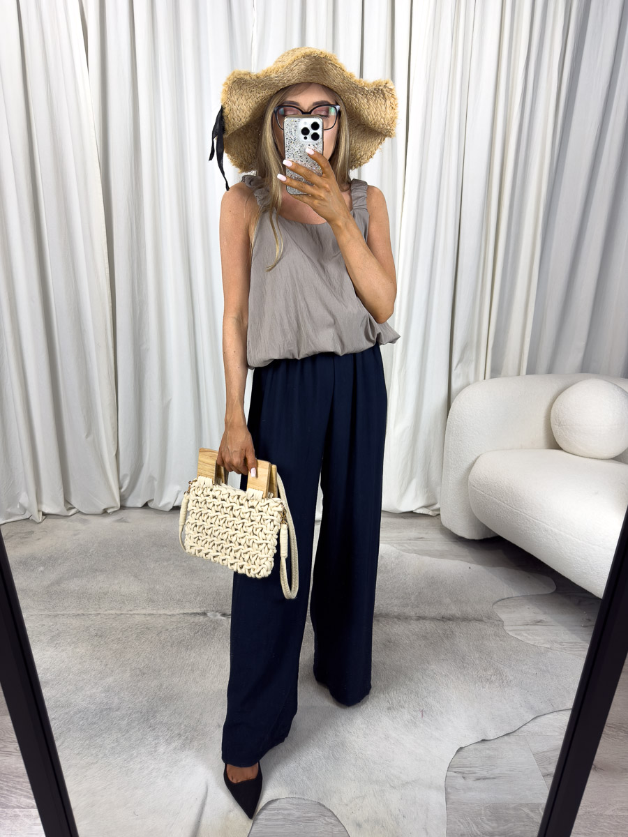 Letnie spodnie June – szerokie spodnie z wysokim stanem na lato, stylizacja z kapeluszem i torebką, zdjęcie na jasnym tle. Zdjęcie produktowe sklepu internetowego z odzieżą damską.
