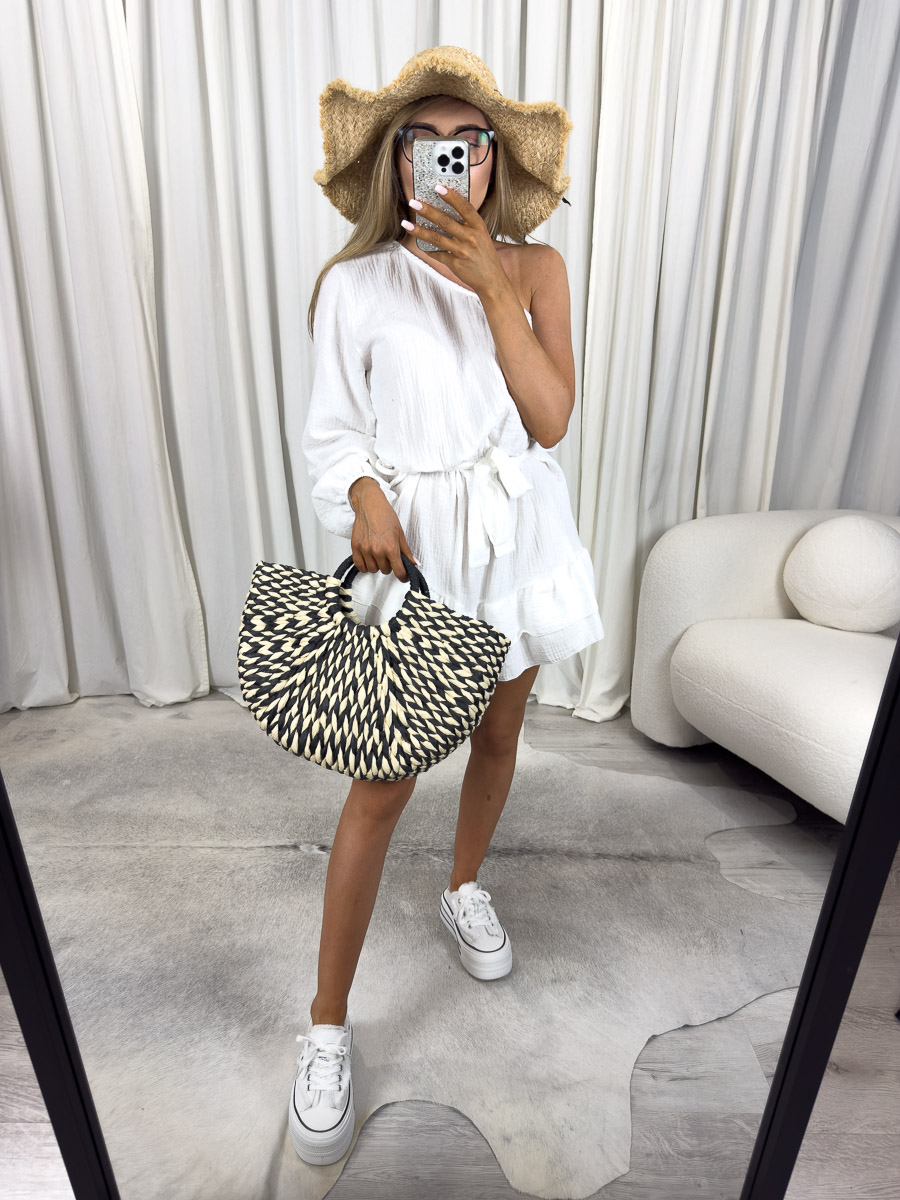 Modelka w muślinowym kombinezonie Girlish z asymetrycznym ramieniem, falbankami i wiązaniem w talii. Zdjęcie produktowe sklepu internetowego z odzieżą damską.