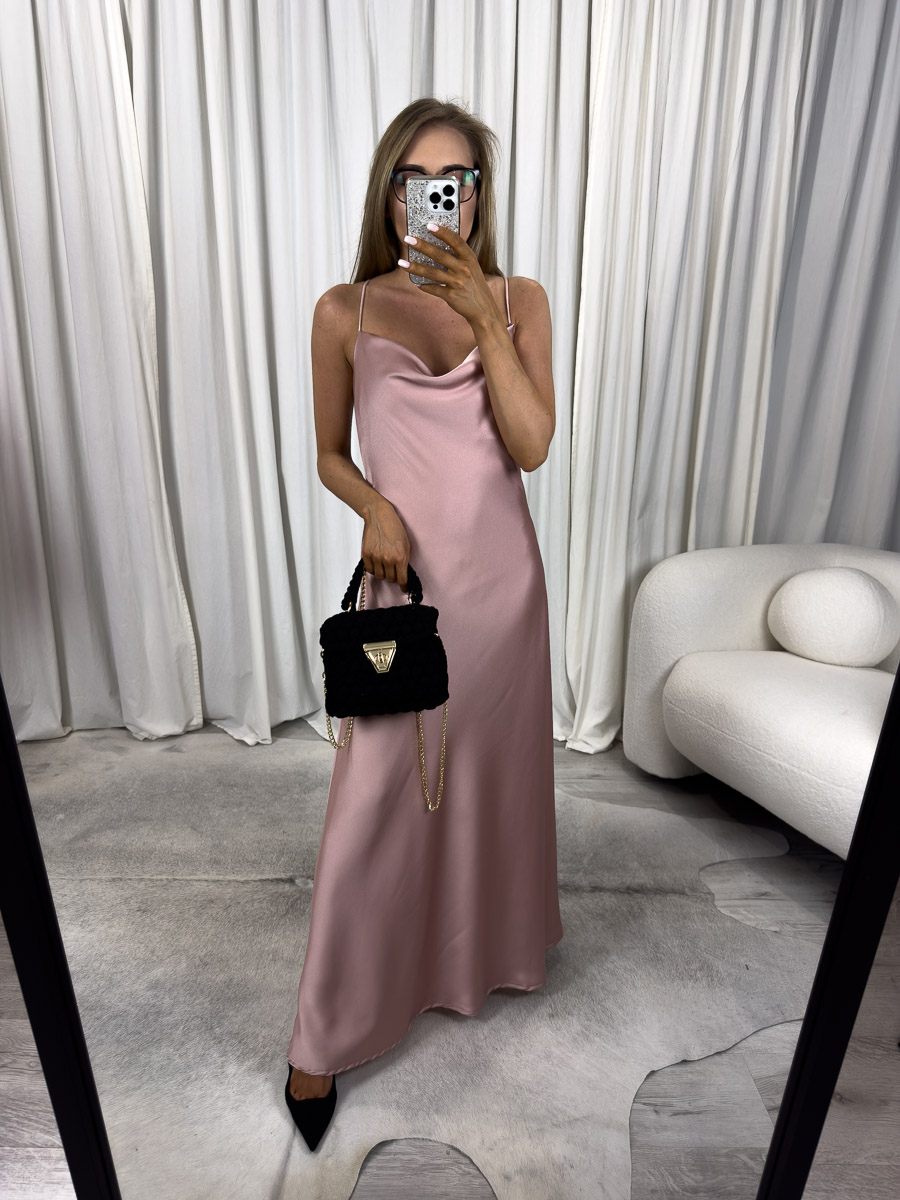Modelka w sukience maxi satynowej Goldie na cienkich ramiączkach z dekoltem typu woda, długa kreacja w kolorze pudrowego różu, zestawiona z czarną torebką i szpilkami – zdjęcie produktowe do sklepu internetowego z odzieżą damską.