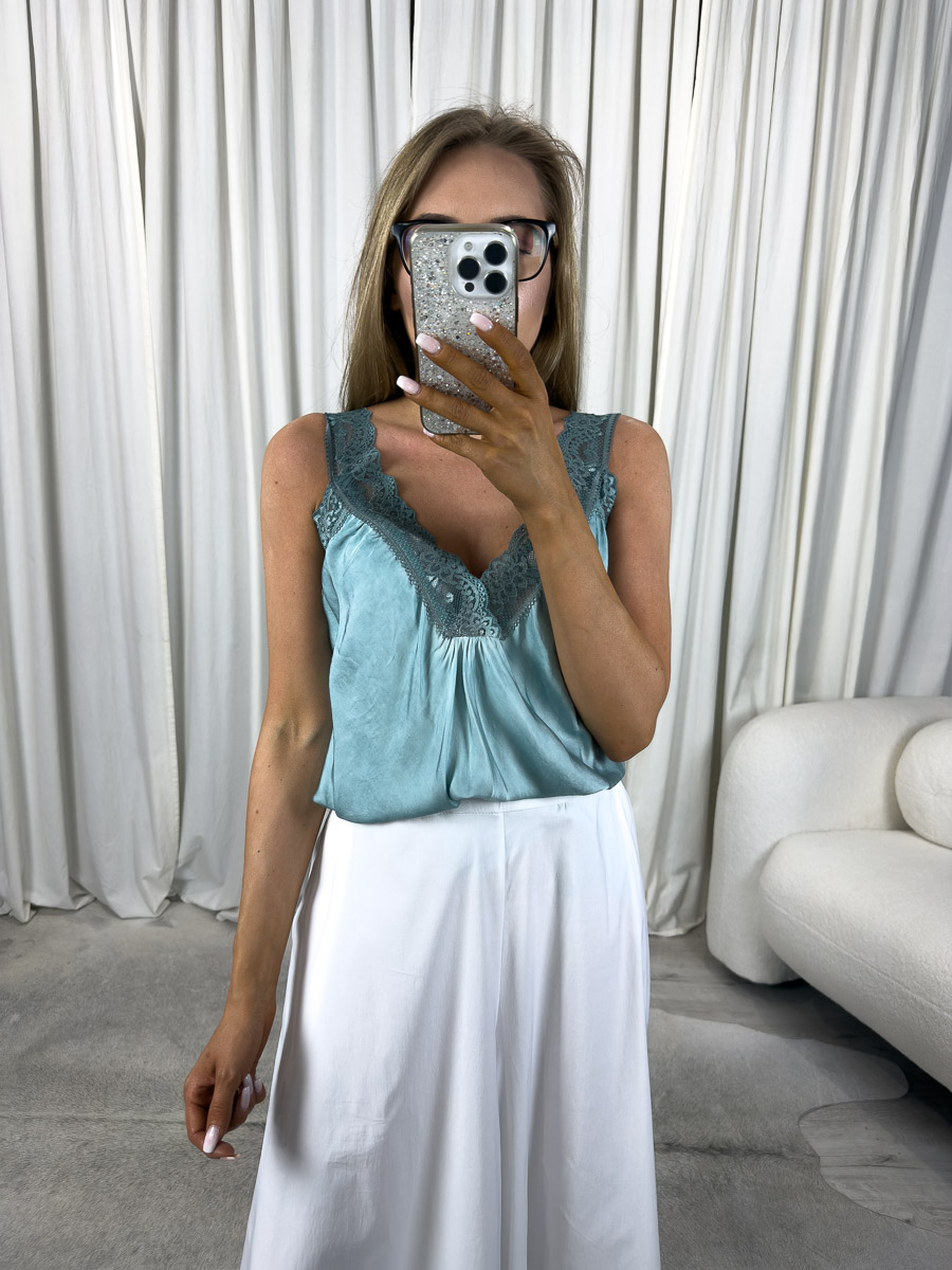 Top satynowy z koronką Sia na cienkich ramiączkach, stylizacja z białymi spodniami. Zdjęcie produktowe sklepu internetowego z odzieżą damską.